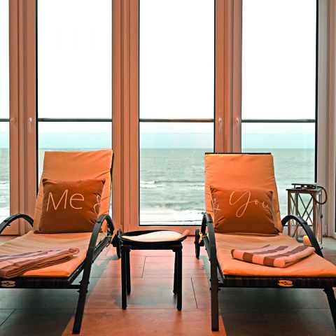 Wellnessbereich Hotel Haus am Meer, zwei Wellnessliegen mit Auflage, Kissen und Decke, zwischen den Liegen Tisch, Blick auf die Ostsee, raue See