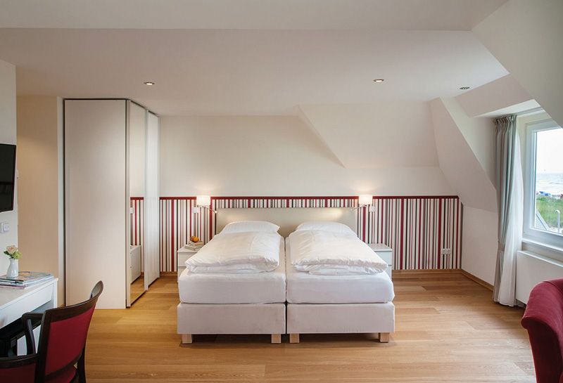 Schlafzimmer des Doppelzimmers. Neben dem Bett stehen Nachtische und kleine Lampen hängen an der Wand darüber