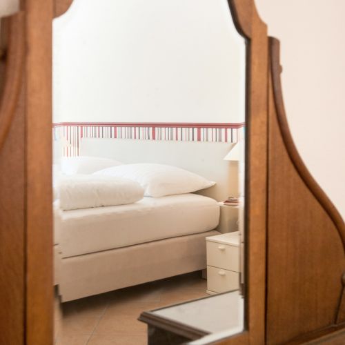 Blick durch den charmanten Holzspiegel auf das frische weiße Bett