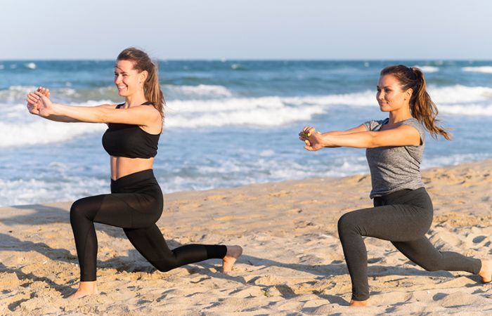 Zwei Frauen am Strand praktizieren Yoga.