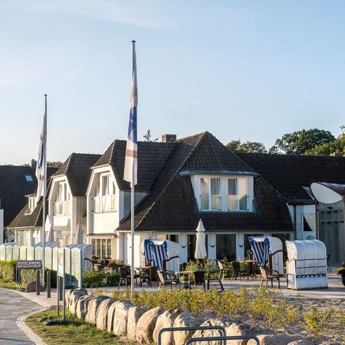 Hotel Haus am Meer Aussenansicht, im Vordergrund Fahnenmaste mit Fahnen, Strandkorbterrasse mit Strandkörben