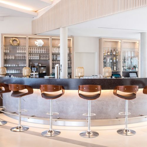 Restaurant Hotel Haus am Meer, Bar, Tresen, Barhocker., hinterm Tresen Wandregale mit Gläsern und Flaschen, auf dem Tresen Rattanlampen