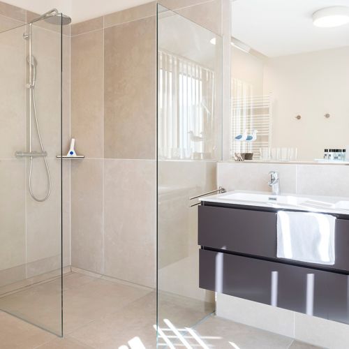 Dusche Penthouse mit modernen Fliesen in grau/braun Tönen, riesigem Spiegel und bodentiefer Dusche