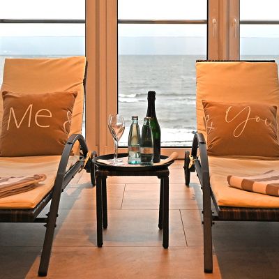 Wellnessbereich Hotel Haus am Meer, zwei Wellnessliegen mit Auflage, Kissen und Decke, zwischen den Liegen Tisch, Blick auf die Ostsee, raue See